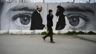 A man wearing a facemask as a precautionary measure against the COVID-19 novel coronavirus walk past a wall painted with images of US Special Representative for Afghanistan Reconciliation Zalmay Khalilzad (L) and Taliban co-founder Mullah Abdul Ghani Baradar (R), in Kabul. (AFP)