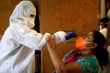 A health worker in personal protective equipment (PPE) collects a swab sample from a woman during a rapid antigen testing campaign for the coronavirus in Mumbai, India, on September 7, 2020. (Reuters)