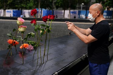 A man takes photos of flowers sitting in names at the north reflecting pool at the National 9/11 Memorial the day before the 19th anniversary of attacks in the Manhattan borough of New York City, New York, US. (Reuters)