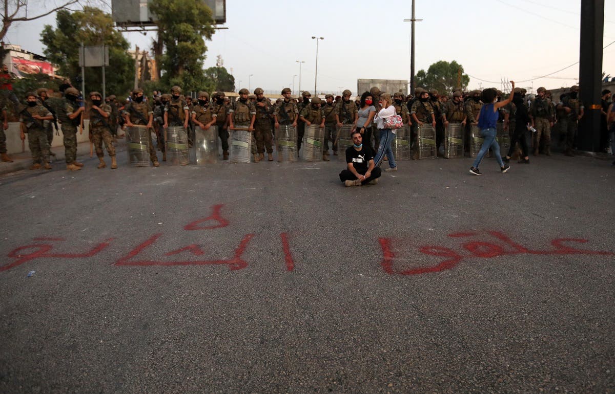 A Lebanese anti-government protester sits in front writing on the ground in Arabic that reads prepare the gallows during a demonstration against the lack of progress in a probe by authorities into a monster blast that ravaged swathes of the capital 40 days ago. (AFP)