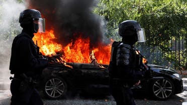 French CRS riot police officers walk past a burning car during a demonstration of the yellow vests movement in Paris. (Reuters)