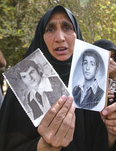 سيدة عراقية تحمل صورة أقارب لها فقدوا خلال عهد البعث في العراق (أرشيفية- فرانس برس)