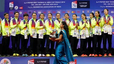2014-05-24An Indian host carries the Uber Cup badminton championship trophy as she walks past the China's team members waiting to receive the trophy after their win in New Delhi May 24, 2014. REUTERST120000Z_99292521_GM1EA5P01LN01_RTRMADP_3_BADMINTON-THOMAS