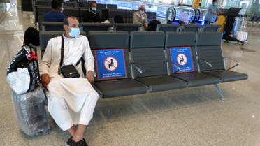 A passenger sits beside posters displaying social distancing restrictions as he waits for his flight at the King Abdulaziz International Airport in Jiddah, Saudi Arabia, Tuesday, July 28, 2020. Few flights are scheduled for international departures only but the authorities have eased domestic travel restrictions since June. (AP Photo/Amr Nabil)