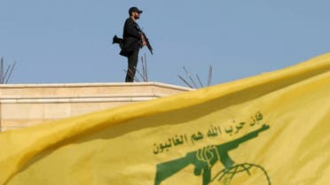 A Hezbollah member carries his weapon on top of a building as Lebanon's Hezbollah leader Hassan Nasrallah appears on a screen during a live broadcast. (File photo: Reuters)