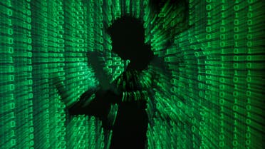 An illustration picture shows a projection of binary code on a man holding a laptop computer, in an office in Warsaw. (File photo: Reuters)