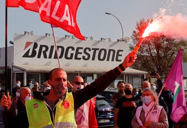 A CGT labour union member, wearing a protective face mask, holds a red flare during a protest with workers in front of the Bridgestone's tyre plant in Bethune, that Japan's Bridgestone plans to shut, France, on September 17, 2020. (Reuters)