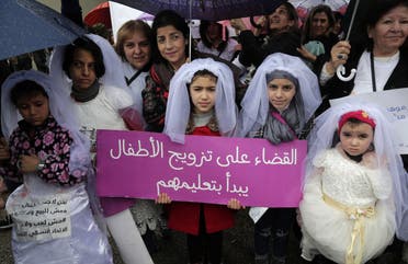 Young Lebanese girls disguised as brides hold a placard as they participate in a march against marriage before the age of 18, in the capital Beirut on March 2, 2019. (AFP)