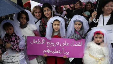 Young Lebanese girls disguised as brides hold a placard as they participate in a march against marriage before the age of 18, in the capital Beirut on March 2, 2019. (AFP)
