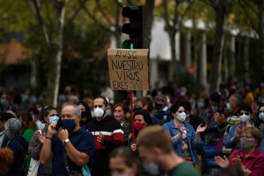 A woman holds a placard reading “Ayuso you are our virus” during a demonstration at the Vallecas neighborhood in Madrid, on September 20, 2020. (AFP)