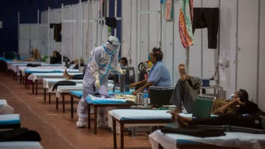 A health worker takes the temperature of a patient at a makeshift COVID-19 care center at an indoor sports stadium, in New Delhi. (AP)