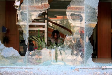 A worker cleans up broken glass from a bank facade after overnight protests against growing economic hardship in Sidon, Lebanon April 29, 2020. (Reuters)