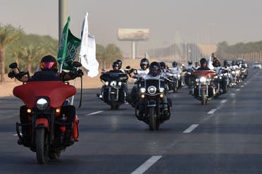 Saudi Arabian and exapt members of the Hawks Riyadh MC club wave a national flag as they ride their motorcycles around the capital Riyadh on September 23, 2020, during a parade to mark Saudi Arabia's national day. (AFP)