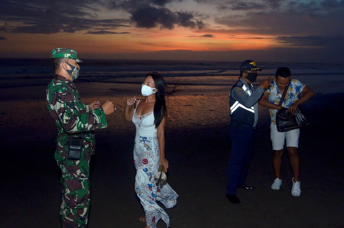 Officers wearing protective face masks give warning to visitors for wearing protective masks, amid the coronavirus disease (COVID-19) outbreak in Badung, Bali Province, Indonesia, on September 3, 2020. (Reuters)