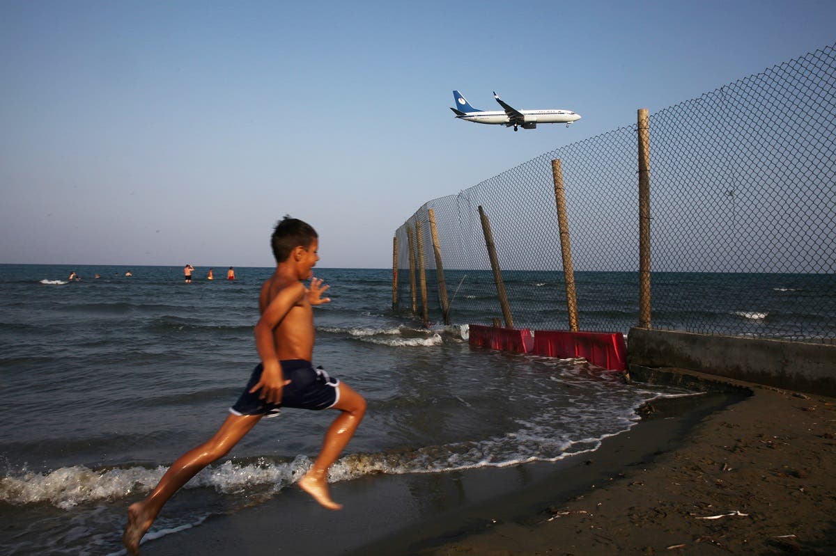 A boy runs on a beach while an airplane prepares to land at Larnaca International Airport, Cyprus. (File photo: Reuters)