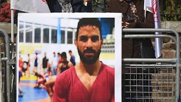 Protesters from two Iranian opposition groups hold a poster of Navid Afkari as they demonstrate outside the Iranian embassy in London. (File photo: AFP)
