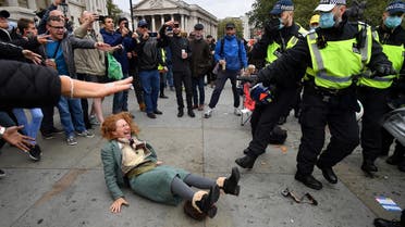 A woman gestures after falling as police move in to disperse protesters demonstrating against coronavirus restrictions in Trafalgar Square in London on September 26, 2020. (AFP)