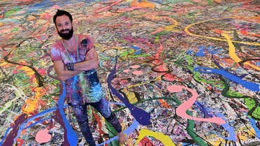 Contemporary British artist Sacha Jafri stands on his record-breaking painting entitled 'The Journey of Humanity'. (AFP)