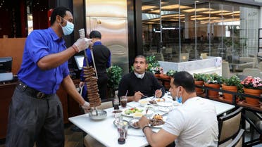A worker wearing a protective face mask and gloves serves food at a restaurant during the reopening of malls, following the outbreak of the coronavirus disease (COVID-19), at Mall of the Emirates in Dubai. (Reuters)