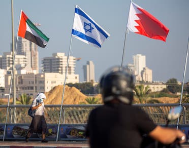 A woman wearing a face mask against the coronavirus pandemic walks past United Arab Emirates, Israel and Bahraini flags in Netanya, Israel on Sept. 14, 2020. (AP)