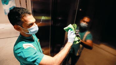 A cleaner wearing a protective mask cleans the elevator doors at the Shangri-La hotel, in Colombo. (Reuters)