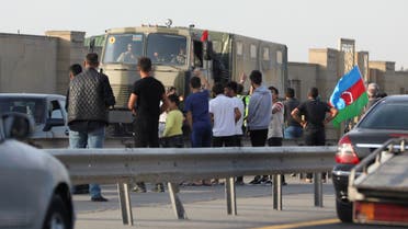 People line up along the roadside to greet Azerbaijani service members, who drive a truck in Baku, Azerbaijan September 27, 2020. (Reuters)