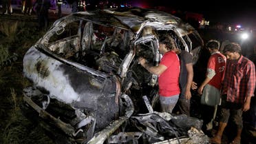 Rescue workers examine a burnt van at the accident site outside of Karachi, Pakistan. (AP)