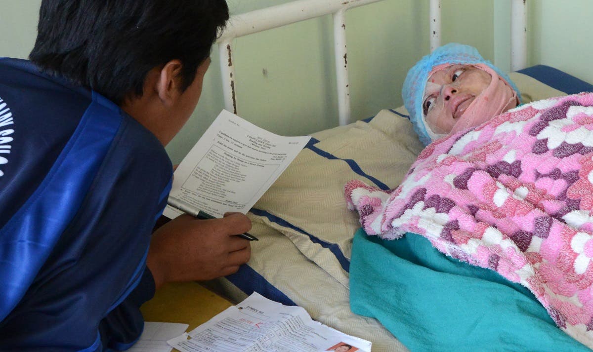 A file photo shows Nepalese acid attack survivor Sangita Magar (R), 16, takes her School Leaving Certificate exam from her hospital bed in Kathmandu on March 19, 2015. (AFP)