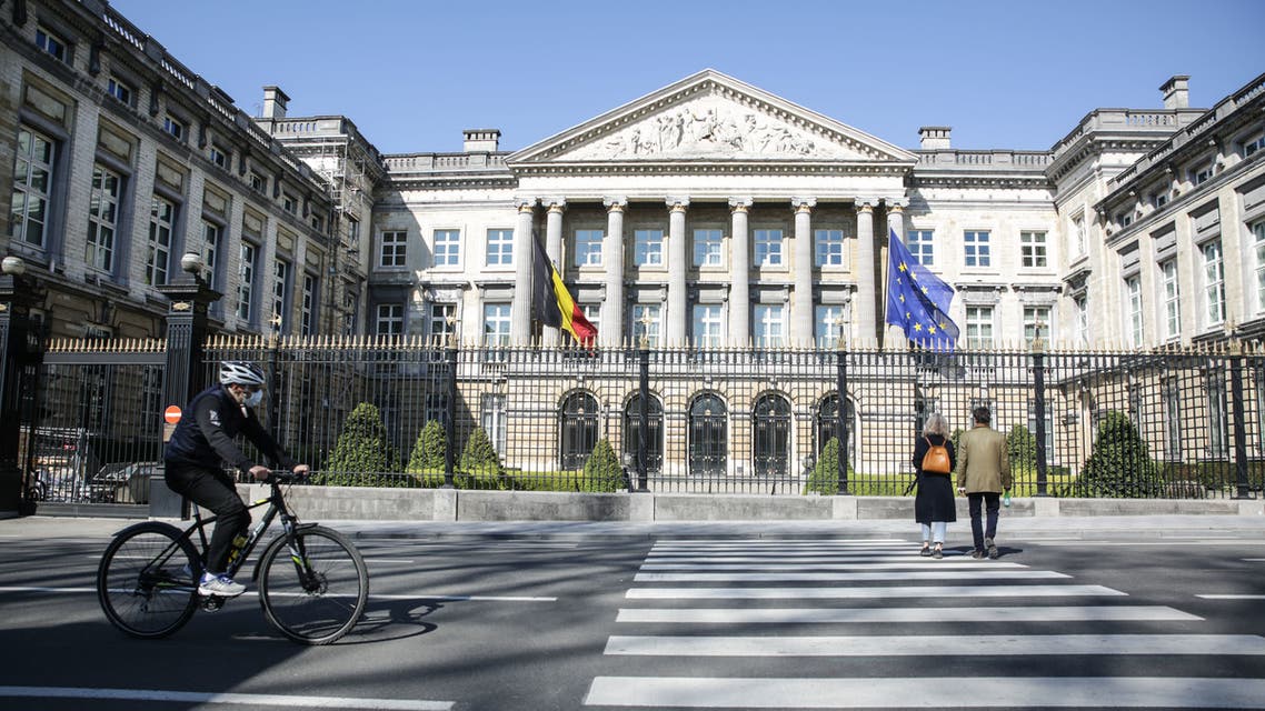 A cyclist wearing protective face mask passes by the Belgian Federal Parliament on April 5, 2020, in Brussels AFP