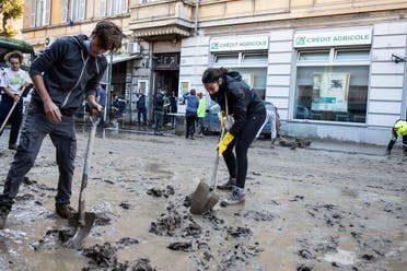 People clean the mud in Ventimiglia, Italy on October 3, 2020 after the Roya river flooded overnight, submerging the whole city with water and mud. (AFP)