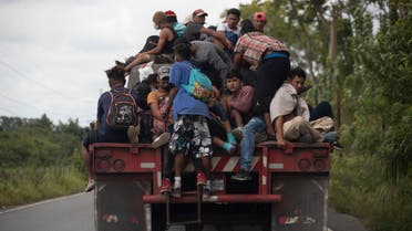 Migrants ride on the back of a freight truck that slowed down to give them an opportunity to jump on in Rio Dulce, Guatemala, Friday, Oct. 2, 2020. (AP)