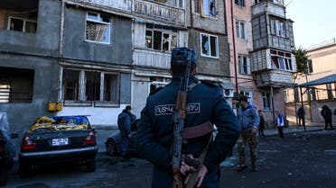 A police officer stands in front of an apartment building that was supposedly damaged by recent shelling in the breakaway Nagorno-Karabakh region's main city of Stepanakert on October 3, 2020, during the ongoing fighting between Armenia and Azerbaijan over the disputed region. (AFP)