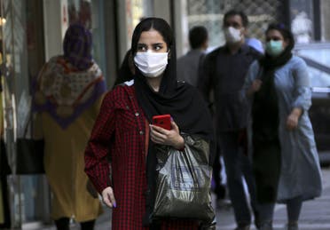 A woman, mask-clad as a COVID-19 coronavirus pandemic precaution, walks past shops along a street in Iran's capital Tehran on September 27, 2020. (AFP)