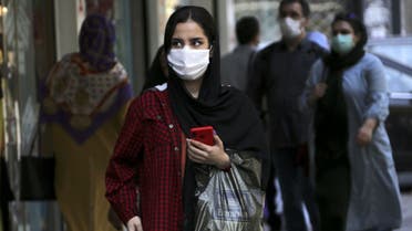 A woman, mask-clad as a COVID-19 coronavirus pandemic precaution, walks past shops along a street in Iran's capital Tehran on September 27, 2020. (AFP)