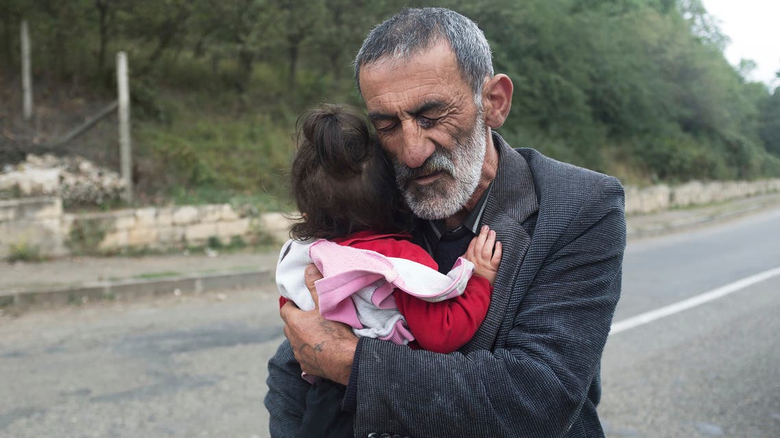A local resident holds his granddaughter in the Hadrut province of self-proclaimed Republic of Nagorno-Karabakh, Azerbaijan on Oct. 1, 2020. (AP)
