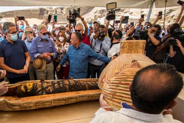 A picture taken on October 3, 2020 shows Egyptian actor Hussein Fahmy (2nd-L) look on as Egyptian Minister of Tourism and Antiquities Khaled Al-Anani (L), and Mustafa Waziri (R), Secretary General of the Supreme Council of Antiquities, unveil the mummy inside a sarcophagus excavated by the Egyptian archaeological mission working at the Saqqara necropolis. (AFP)