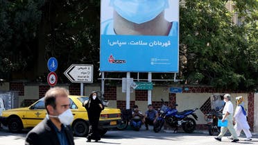 Iranians, wearing protective face masks, walk under a billboard thanking first responders in the capital Tehran on July 22, 2020, during coronavirus pandemic. (Atta Kenare/AFP)