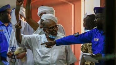 Sudan’s ousted president Omar al-Bashir (C) speaks to a police officer as he arrives for his trial in the capital Khartoum, on October 6, 2020. (AFP)