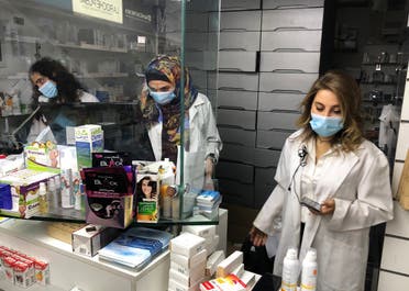Pharmacist Siham Itani wearing a protective mask looks at her mobile phone inside her pharmacy in Beirut, Oct. 6, 2020. (Reuters)