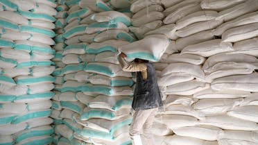 Workers handle sacks of wheat flour at a World Food Programme food aid distribution center in Sanaa. (Reuters)