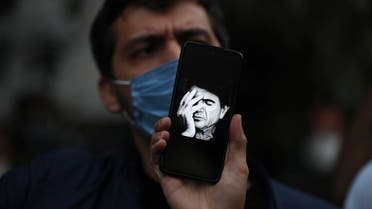 A fan displays an image of the nation's famous singer Mohammad Reza Shajarian on his phone, outside the Jam Hospital where Shajarian died of cancer at the age of 80, in Tehran. (AP)