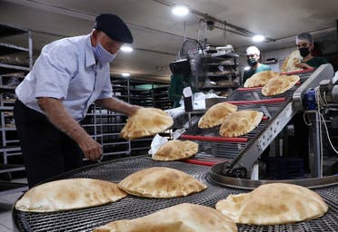 Workers wearing protective masks prepare baked breads inside a bakery in Beirut, Oct. 8, 2020. (Reuters)