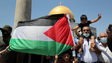 People hold a Palestinian flag during a protest against the United Arab Emirates, in Jerusalem's Old City, August 14, 2020. (Reuters)
