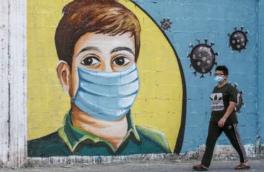 A Palestinian boy walks past a coronavirus awareness mural in Rafah in the southern Gaza Strip on September 14, 2020. (AFP)