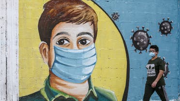 A Palestinians boy walks past a coronavirus awareness mural in Rafah in the southern Gaza Strip on September 14, 2020. (AFP)