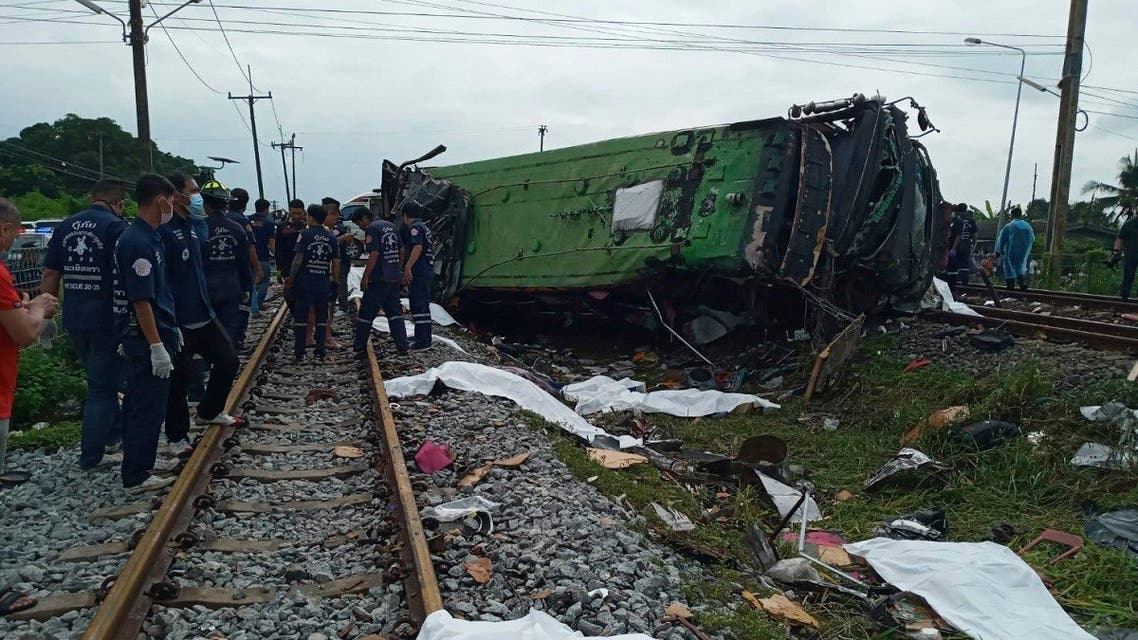 Rescuers stand by a damaged train and bodies covered with white sheets after a bus-train collision in Thailand. (AP)