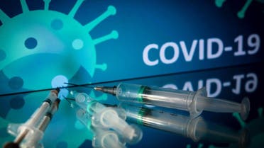 This photograph taken on October 7, 2020 shows syringes on an illustration representing coronavirus, in Toulouse, southwestern France. (AFP)