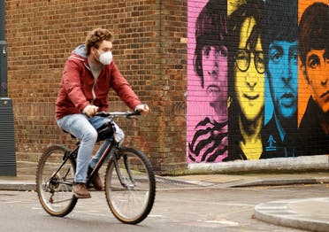 A man wearing a protective mask rides a bike past a mural depicting members of The Beatles, amid the outbreak of the coronavirus disease (COVID-19), in Liverpool, Britain October 13, 2020. (Reuters)
