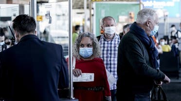 Passengers wearing protective face masks queue at the boarding gate at Brussels Airport, in Zaventem, on June 15, 2020. (AFP)