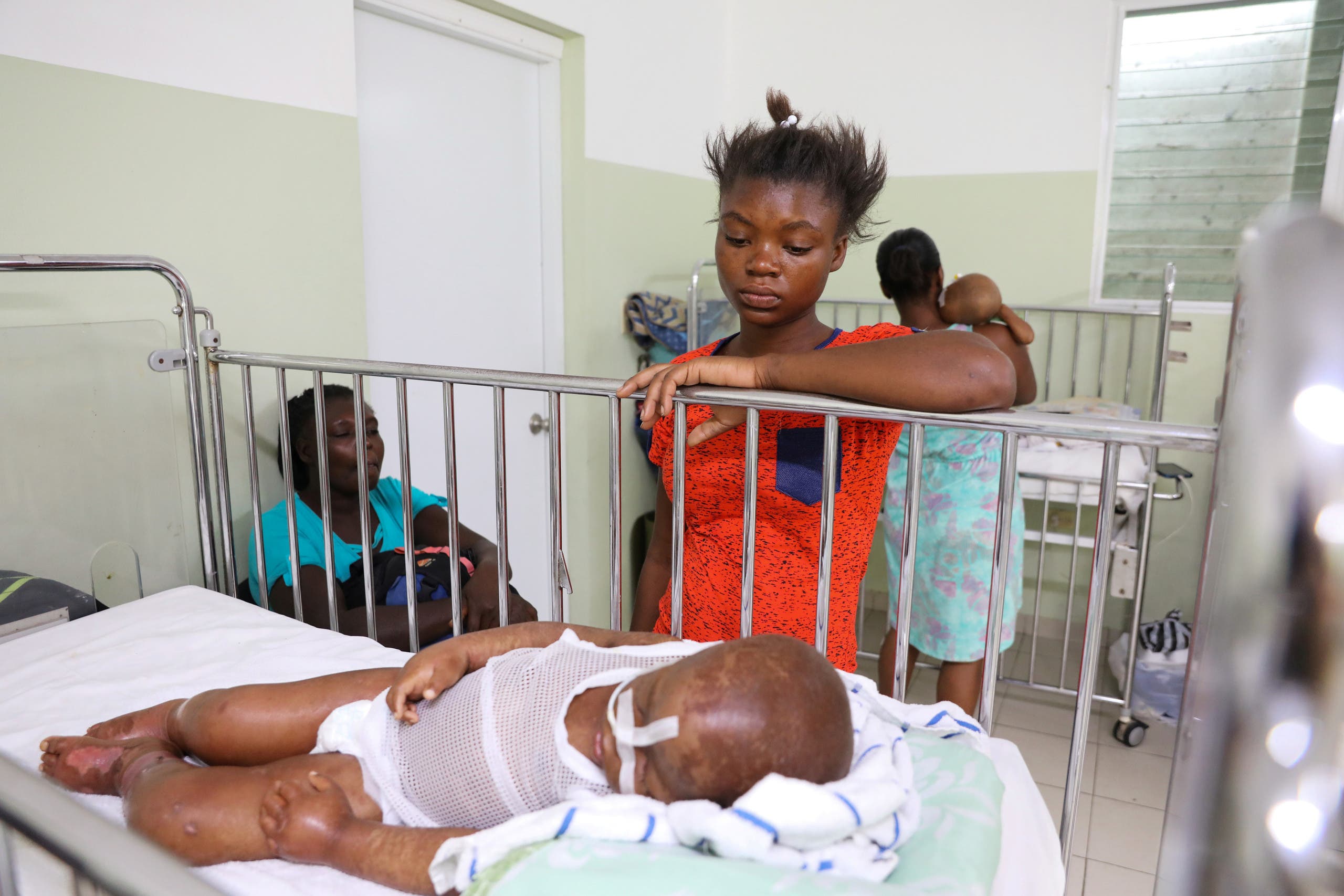 أم تقف جنب طفلهتا في جناح الأطفال المصابين بسوء التغذية في مستشفى بهايتي في يناير الماضي